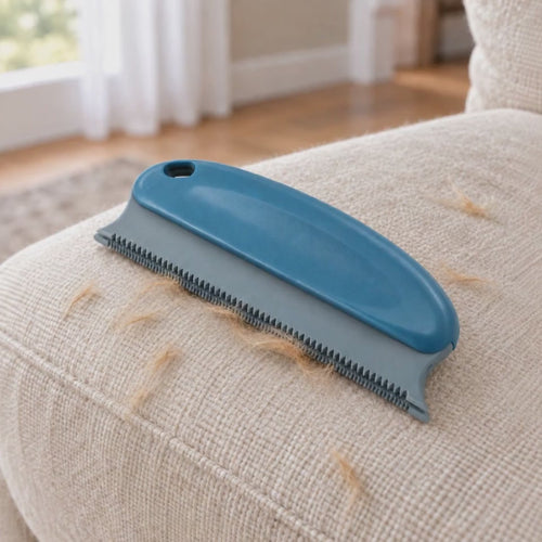 Hand pulling the blue FurProof brush across a cream sofa, gathering dog hair